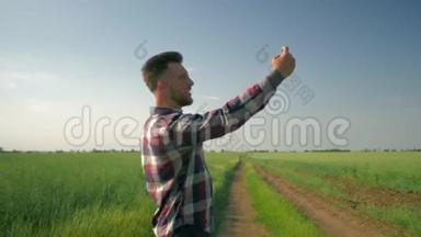 穿格子衬衫的开朗的农民<strong>手持</strong>手机，在绿野蓝天的背景下自<strong>拍照</strong>片